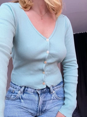 Ribbad topp med knappar - En ribbad långärmad topp med knappar. Toppen är turkos, i storlek M och kommer från Chiquelle. Passar mig bra som normalt har S 🥰💖  Använd max 3 gånger 🙌🏻  Längd: 43 cm Axel: 31 cm