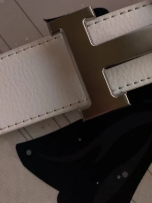 Bälte med h-spänne vitt 110cm - Snyggt vitt bälte med h-spänne 110cm lång. Skickar fort