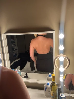 Svart halterneck korsettopp - Säljer en svart halterneck korsettopp med djup v-ringning och öppen rygg. Toppen har figurnära passform och markerad midja, vilket ger en snygg siluett. Perfekt att styla med både byxor och kjol för en trendig look.