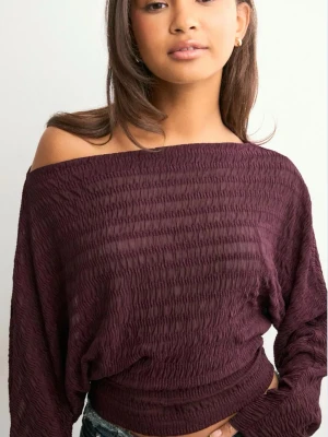 Vinröd offshoulder topp - Säljer en vinröd offshoulder topp med smockad struktur och lång ärm. Toppen har en croppad passform och är perfekt för dig som gillar en trendig och avslappnad stil. Materialet är mjukt och stretchigt, vilket gör den bekväm att bära. Är i storlek m men passar både mindre och större 