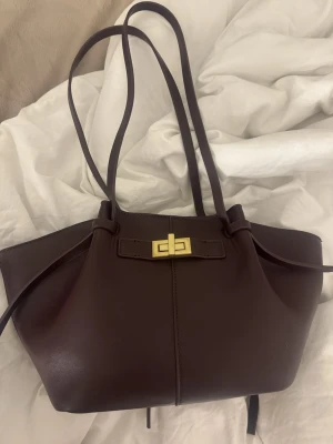 axelväska från Gina Tricot - Snygg axelväska från Gina Tricot i slätt skinnimitation. Väskan har långa axelband, guldfärgat vridlås och enkel, stilren design. Perfekt storlek för att få plats med allt du behöver och har en innerficka med dragkedja. ( erbjuder gärna att byta med nån som har en samma fast i brun !! ) 