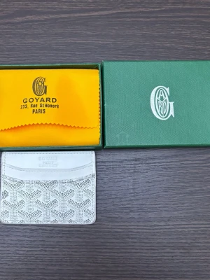 Vit kortfodral  - Supersnyggt vitt kortfodral med ikonisk mönster. Fodralet har flera kortfack och är gjort i skinn med ett stilrent och lyxigt uttryck. Perfekt för dig som vill ha något både praktiskt och trendigt i fickan. Tar emot bud. Köpt är köpt