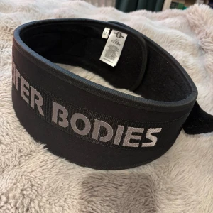 Svart träningsbälte Better Bodies - Säljer ett svart träningsbälte från Better Bodies i storlek M. Det har en rejäl spänne för extra stöd vid tunga lyft. Perfekt för gymmet!