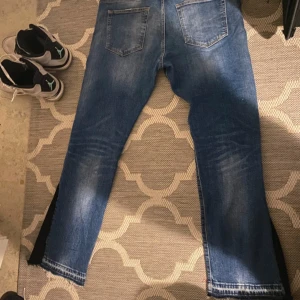Blå slitna jeans med trasiga detaljer - Säljer ett par blå jeans från Dr. Denim med trasiga detaljer och slitningar framtill. Jeansen har klassisk femficksdesign, raka ben och fransad nederkant. Materialet är 99% bomull och 1% elastan för lite stretch. Perfekta för en avslappnad streetstil.