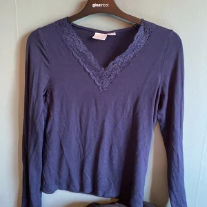 Mörkblå långärmad topp med spets - Mörkblå långärmad topp från Gina Tricot med snygg v-ringning och spetsdetalj runt halsen. Tillverkad i mjuk bomull, perfekt för dig som gillar en enkel men ändå söt stil. Passar till både jeans och kjol.