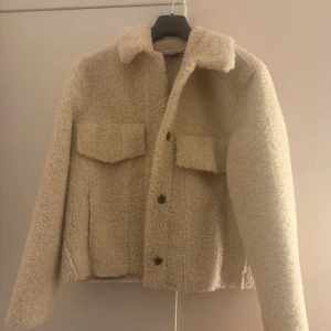 Zara teddyjacka beige - Jackan har en avslappnad passform, två stora fickor framtill och knäppning med tryckknappar. Perfekt för höst och vår eller som ett lager under kallare dagar. Storlek Xs och passar som S😊använt enstaka gånger