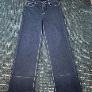Blå raka jeans från LMTD, stl M - Snygga blå jeans från LMTD i rak modell med kontrastsömmar och klassiska fem fickor. Jeansen har hög midja och är tillverkade i ett rubust denimtyg som ger en clean och stilren look. Perfekta för dig som gillar en enkel men trendig stil.
