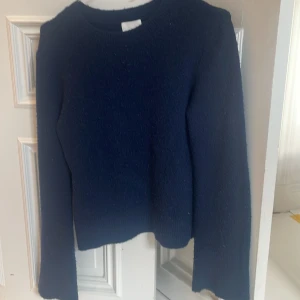 Mörkblå stickad tröja - En enkel och stilren mörkblå stickad tröja med rund halsringning och långa ärmar. Perfekt för lager-på-lager och passar till både jeans och kjol. Mjuk och skön känsla, ett måste i garderoben för kyligare dagar.