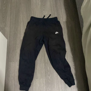 Svarta mjukisbyxor från Nike L - Svarta mjukisbyxor från Nike med klassisk logga på vänster lår. Byxorna har resår och snörning i midjan samt muddar vid bensluten. Perfekta för chill eller träning, tillverkade i mjukt material för extra komfort.Väldigt röd men går och använda 