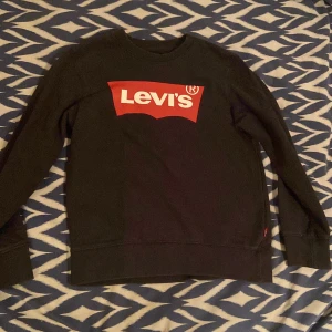 Svart Levi's sweatshirt. Storlek 140cm. - Svart sweatshirt från Levi's med den klassiska röda och vita loggan framtill. Tröjan har rund hals, långa ärmar och ribbade muddar. Perfekt för dig som gillar en enkel och stilren look med streetkänsla. Storlek 140cm