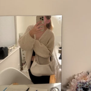 Beige axelväska i flätat skinn - Säljer en snygg beige axelväska i flätat skinn. Väskan har en mjuk, rundad form och ett stilrent, minimalistiskt uttryck. Perfekt storlek för det viktigaste och med dragkedja upptill. Passar dig som gillar trendiga accessoarer med en clean look.