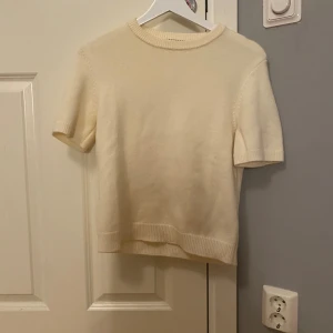 Vit stickad kortärmad tröja Gina Tricot - Superfin vit stickad tröja från Gina Tricot i storlek XS. Tröjan har korta ärmar, rund halsringning och ribbade kanter vid ärmslut och nederkant. Perfekt för lager-på-lager och enkel att matcha med allt.