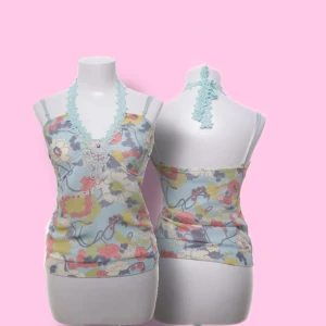 Blommig linnetopp med spets från Vila - Supersöt linnetopp från Vila i ljusblått med färgglatt blommönster i gult, rött, vitt och lila. Toppen har smala axelband, v-ringning med turkos spets och dekorativ spetsdetalj framtill. Perfekt för dig som gillar romantiska och unika detaljer.