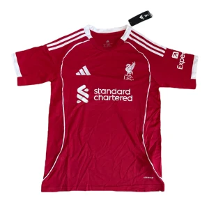 Liverpool FC röd matchtröja Adidas - Liverpool FCs officiella matchtröja från Adidas i rött med vita detaljer och broderad LFC-logga. Tröjan har klassiska tre ränder på axlarna, vit krage och ärmslut samt tryckta sponsorer. Tillverkad i lätt och ventilerande polyester.