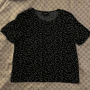 Svart prickig topp från Monki - Svart topp från Monki med vita prickar över hela tyget. Modellen har rund halsringning och korta ärmar. Köpt ny för något år sedan och använd endast en gång😊👍🏼