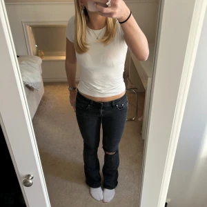Svarta bootcut jeans med hål på knät - Säljer ett par svarta lågmidjade jeans från laget 157. Hålet på knät är gjort själv! Byxorna är ganska använda men inget som märks på dom. Dom är försmå och för korta för mig så tänk bort de på bilderna!!