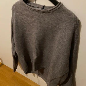 Grå stickad tröja  - Mysig grå stickad tröja med rund halsringning och långa ärmar. Enkel och stilren design som passar perfekt till jeans eller kjol. Tröjan har en normal passform och är tillverkad i ett mjukt stickat material. (36-38)