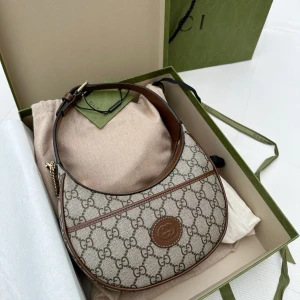 Gucci GG Supreme axelväska beige/brun - Säljer en ikonisk Gucci axelväska i GG Supreme-mönster. Väskan är halvmåneformad i beige canvas med bruna skinn-detaljer och guldiga metalldelar. Klassisk logga framtill och dragkedja upptill. Perfekt storlek för det viktigaste och riktigt snygg att bära crossbody.