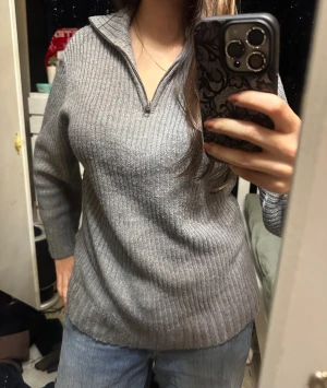 Grå ribbstickad half zip-tröja - Säljer en grå ribbstickad tröja från H&M med half zip-dragkedja och hög krage. Tröjan är långärmad och har en relaxed fit, perfekt för lager på lager. Materialet är mjukt och stretchigt, vilket gör den superbekväm :)