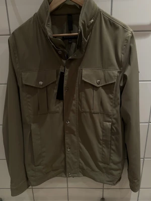 J.Lindberg field jacka  - Hej! Jag säljer nu denna HELT nya och fantastiskt fina jackan från J Lindberg. Klassisk fieldjackedesign med fyra fickor fram till och två praktiska innerfickor vid brösten. Passform M men skulle säga att denna är M/L Kvitto tillkommer och nypris ligger på 3299kr mitt pris är endast 1399kr. Hela 1900kr rabatt. Perfekt i julklapp nu till jul. Passa på och fynda denna otroliga jackan från J Lindberg. Köp till något mer i profilen och få 50% rabatt på billigaste plagget! Vid frågor kontakta oss!