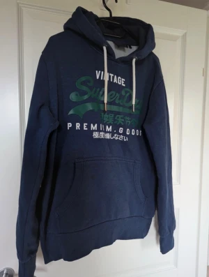Superdry hoodie - Snygg hoodie, mörkblå med grön text, grymt skick.