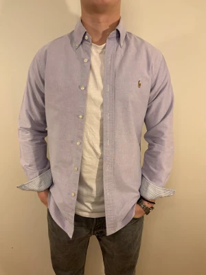 Ljuslila Ralph Lauren skjorta - En stilren skjorta från Ralph Lauren Second hand men i väldigt fint skick ✨ Tvättad och struken – redo att användas direkt.  Perfekt för en lite festligare look med väldigt snygga mönster i ärmslut samt krage.  Inga defekter och slim fit.  Storlek 👔: M Nypris 💰: ca 1 300 kr 