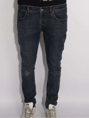 Mörkblå skinny jeans från Tiger of Sweden - Snygga mörkblå jeans från Toger of Sweden med klassisk femficksdesign och smal passform. Jeansen har låg midja och är tillverkade i slitstarkt denim med subtila kontrastsömmar. Perfekta för dig som gillar en tajt siluett och vill ha en tidlös look.