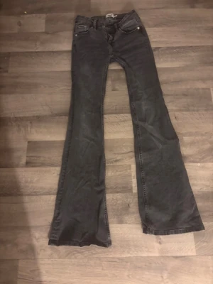 Svarta bootcut jeans från 157, XS - Svarta jeans från 157 i storlek XS med full längd. Modellen har klassisk femficksdesign och bootcut-ben som ger en snygg siluett. Jeansen är gjorda i ett mjukt denimtyg och har knapp och dragkedja framtill. Perfekt för dig som gillar en lite retro vibe.