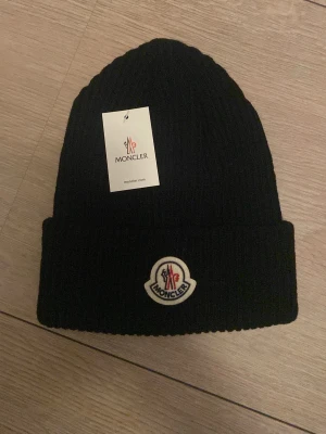 Moncler mössa - Säljer nu denna stilrena och varma moncler mössan perfekt till vintern och för dig som vill vara lite bättre och finare än alla andra. Mössan är helt oanvänd och tags sitter kvar. Vid frågor eller liknande kontakta, vänlig hälsning Kalllejuan😃Pris kan diskuteras🚨