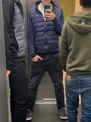 Mörkblå cardigan Calvin Klein M - Snygg mörkblå pufferjacka från Calvin Klein Golf med quiltad front och dragkedja. Jackan har långärmade partier i stickad polyester och en liten CK-logga på bröstet. Perfekt för dig som vill ha en sportig och modern look.