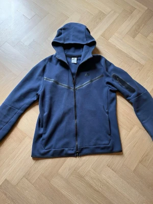 Nike tech - Nike tech fleece skick 7/10🤩Finns ett litet hål i fickan som är så litet att man inte märker av det om man inte känner nogrant efter det. Finns även några pytte små hål vid bröstet som man inte ens ser med blåtta ögat men kollar man noga ser man dem nog se bild 2