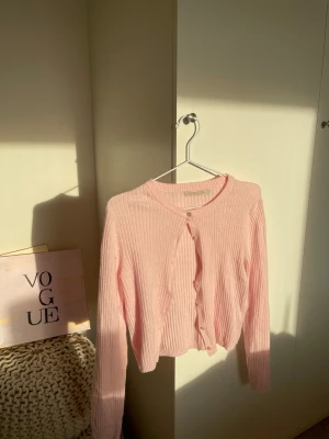 Ljusrosa ribbad kofta från lager 157 - Säljer en ljusrosa ribbad kofta från lager 157 i storlek S. Koftan har rund hals, långa ärmar och knappar framtill. Materialet är mjukt och stickat, perfekt för lager-på-lager. Enkel och clean design som är lätt att matcha med olika outfits. Bara använd en gång 💞