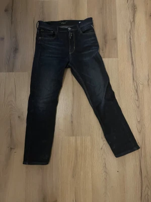 Mörkblå Replay jeans  - Snygga mörkblå jeans från Replay, modell THAD, med klassisk femficksdesign och kontrastsömmar. Jeansen har rak passform och är tillverkade i slitstarkt bomullsmaterial. Perfekta för dig som gillar stilrena och tidlösa jeans.