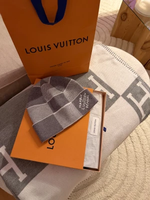 Louis Vuitton Damier Heritage Mössa - Säljer en snygg oanvänd Damier mössa från Louis Vuitton pågrund av att den var för liten för mitt XL huvud dvs 60cm men passar bra på large/medium användare. Mössan är stickad och har en modern look som passar perfekt till kalla dagar. (SNABB AFFÄR-BÄTTRE PRIS❤️) OBS! Säljer inte med originalförpackningen.