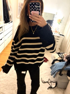 Svartvit randig stickad tröja - Oversized stickad tröja med breda svarta och vita ränder. Tröjan har långa ärmar, rund halsringning och ribbade muddar. 