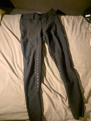 Svarta leggings från Maya Delorez XS - Säljer ett par svarta leggings från Maya Delorez i storlek XS. De har hög midja och silikonmönster på insidan av benen för extra grepp. Perfekta för dig som vill ha både stil och funktion i ridningen. Helskodda! 