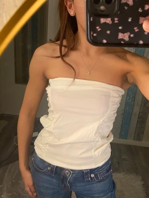 Vit bandeau tubtopp - Mjuk och stretchig tubtopp med rynkade sidor + kedja. Toppen är axelbandslös!! :) sällan använt. Storlek XS o S
