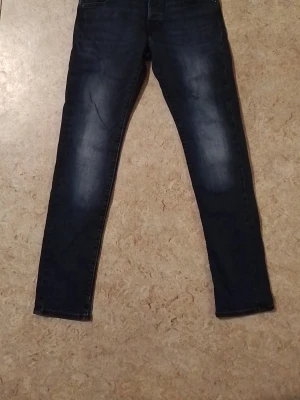 Mörkblå skinny jeans med tvättade detaljer - Snygga mörkblå skinny jeans med lätt tvättade partier på låren och knäna. Klassisk femficksmodell med smal passform och normal midja. Perfekta för en trendig och avslappnad look. Jag säljer den för att jag behöver pengar.