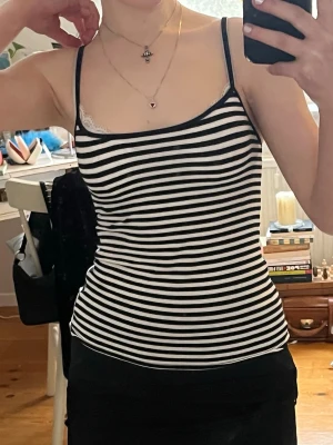 Randig svartvitt linne - Snygg randig linnetopp med smala axelband i svart och vitt. Linnet är i storlek 34.