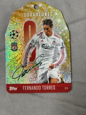Match Attax Squadzone Fernando Torres - Exklusiv Match Attax Squadzone-samlarbricka med Fernando Torres i Liverpool-tröja, nummer 9. Brickan har holografisk yta, autograftryck och klubbmärke. Perfekt för fotbollssamlare och fans av Champions League. Köparen står för frakten.