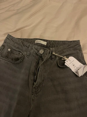 Gråa full length  jeans från Gina tricot  - Snygga grå jeans från gina med klassisk femficksdesign och raka ben. Jeansen har en silverfärgad knapp och dragkedja i gylfen. Perfekta för dig som gillar en enkel och stilren look. Aldrig använda så helt nya, prislappen är kvar