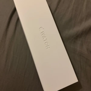 Smart Watch i vit originalförpackning - Smart Watch i elegant vit originalkartong. Klassisk och stilren design, perfekt för dig som vill ha koll på både träning och notiser direkt på handleden. Förpackningen är av hård kartong med präglad logga.