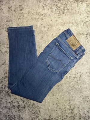 Jacob Cohën jeans - Säljer dessa mörkblåa Jacob Cohën jeans i storlek 30. De är i fint skick utan några synliga defekter, insidan av en ficka har några stygn sydda för att laga ett hål. Hör gärna av dig vid minsta fundering!