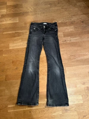 Svarta bootcut jeans med slitningar - Jeans från Gina tricot i storlek 146 grå-svarta. .Snygga svarta jeans med bootcut-modell och lätt slitna detaljer framtill. Jeansen har klassiska fem fickor och knäppning med dragkedja. Bakfickorna har lock med knapp. Perfekta för en avslappnad och trendig look.