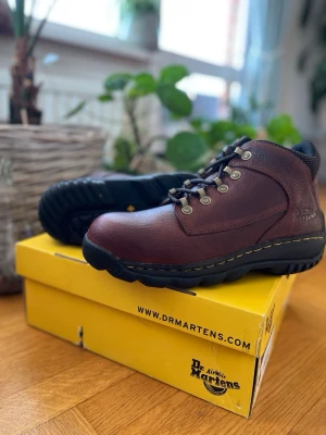 Dr. Martens Outdoor Boots – Helt nya - Helt nya i kartong, 100 % äkta Dr. Martens 7A52 Outdoor-kängor. Aldrig använda och i absolut nyskick. Storlek: 43 • Färg: Teak (mörkbrun) läder • Egenskaper: Kraftig TRED-sula, vadderat skaft och detaljer i industrikvalitet. En ovanlig modell som är byggd för att hålla i ur och skur. Levereras i originalkartong.