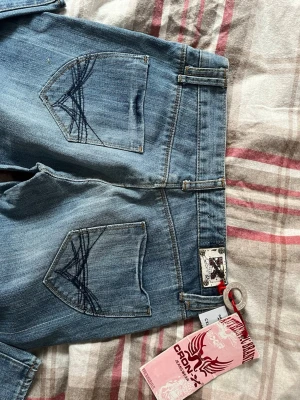 Blåa low waist jeans  - Snygga ljusblå jeans medunika broderade detaljer på bakfickorna. W28 och L32 💗💗 Säljer dem pga de är för små för mig ❤️‍🩹