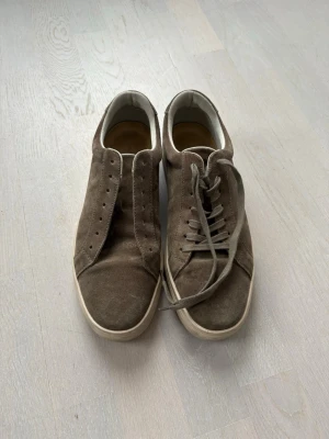 Brun/Beige Vagabond Paul 2.0 - Snygga bruna sneakers i mocka med klassisk rund tå och vita sulor. Skorna har snörning och en stilren, minimalistisk design som passar till det mesta. Insidan är fodrad i vitt material för extra komfort. Ena skon saknar snöre men kan lätt lösa det för en liten extra peng.