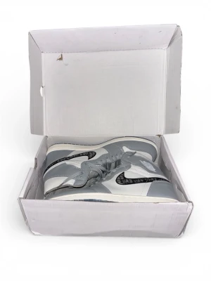 Nike Air Jordan 1  - Exklusiva Nike Air Jordan 1 sneakers i grått och vitt skinn med ikoniska nike swoosh och högt skaft. Snygg design med snörning och rund tå, levereras i original Air Jordan låda. Perfekta för dig som vill sticka ut med stil.