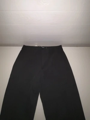 Svarta byxor från BikBok, storlek 36 - Snygga svarta byxor från BikBok i storlek 36. Klassisk rak modell med hällor för bälte och enkel design som passar till många olika stilar. Tillverkade i ett mjukt och bekvämt material som känns skönt hela dagen.