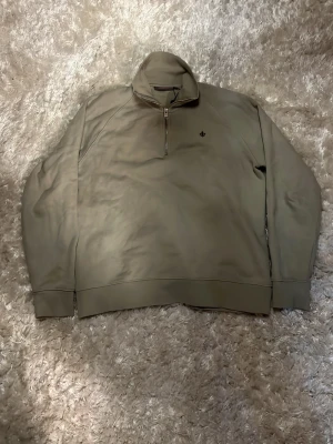 Beige half zip tröja från Morris - Snygg beige tröja från Morris med half zip och hög krage. Tröjan har lång ärm och diskret logga på bröstet. Perfekt för en clean och stilren look.